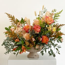 Peach and coral rose arrangement in a pedestal vase
