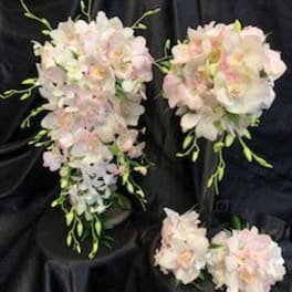 Pastel orchid bouquets with cascading blooms on a dark fabric background