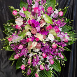 Large pink and white floral spray with tropical leaves on a black backdrop