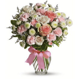 Pink and white rose bouquet in a clear glass vase with a pink ribbon