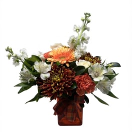 Mixed bouquet in an amber vase with orange, white, and burgundy flowers