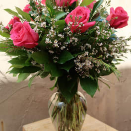Pink roses arranged in a clear glass vase with small white filler flowers