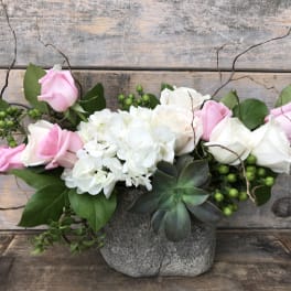 Pink and white roses with white hydrangeas in a gray stone vase