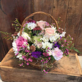 Basket arrangement of pink and white flowers with a wicker handle
