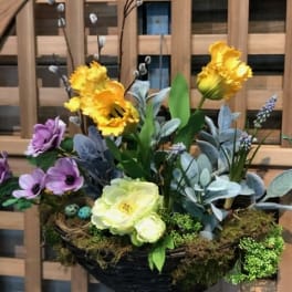 Basket arrangement with yellow and purple flowers and moss