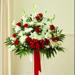 Red and white floral standing arrangement with a red ribbon on a metal stand