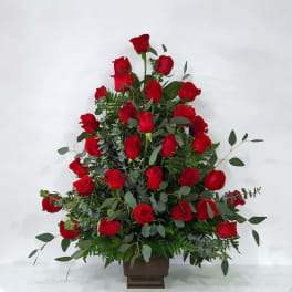 Tall arrangement of red roses in a brown vase
