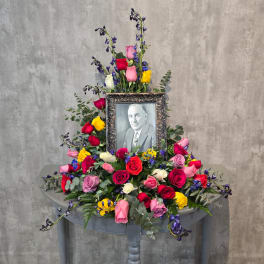 Colorful rose arrangement around a framed black-and-white portrait
