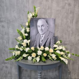 White floral arrangement around a black-and-white portrait on a table