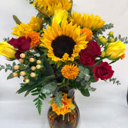 Sunflower and red rose bouquet in a dark glass vase