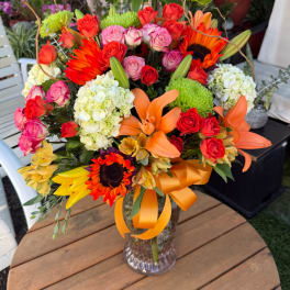 Colorful bouquet of roses, lilies, hydrangeas, and sunflowers in a glass vase