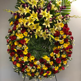 Large standing floral spray with yellow lilies, red roses, and purple orchids