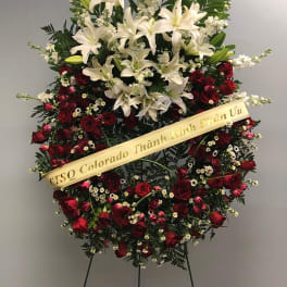 Standing floral wreath with white lilies and red roses on an easel