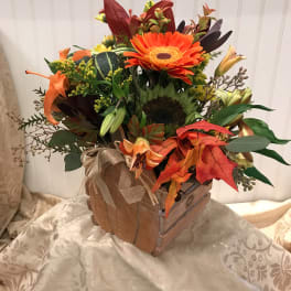 Autumn floral arrangement in a wooden box with orange gerbera daisies and lilies