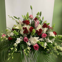 Large floral arrangement with red, pink, and white blooms in a low container