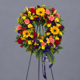 Colorful standing floral wreath on an easel with a purple ribbon