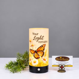 Butterfly memorial candle with daisies and the words "Your Light remains"