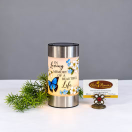 Memorial candle in a stainless steel holder with floral and butterfly design