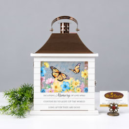 Decorative memorial lantern with butterfly and flower panel, plus a small potted plant