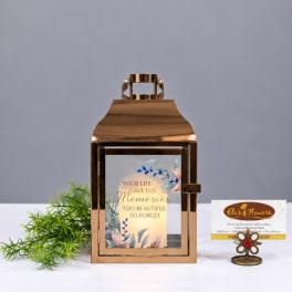 Copper lantern with a memorial message card and small decorative plant