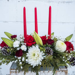 Holiday centerpiece with red candles, roses, white blooms, and pinecones