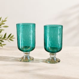 Two teal glass goblets with textured surfaces on a light tabletop