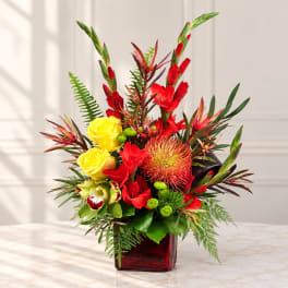 Tropical bouquet with red and yellow flowers in a red glass vase