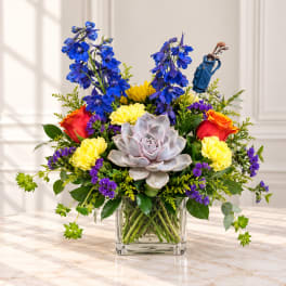 Colorful bouquet in a clear square vase with a golf-themed pick