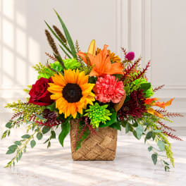Colorful mixed flower arrangement in a woven basket container