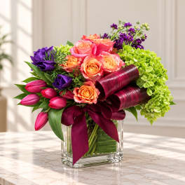 Colorful bouquet of roses, tulips, and hydrangeas in a clear glass vase