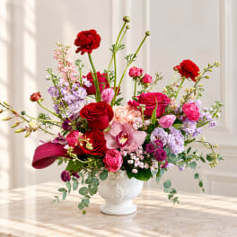 Mixed bouquet of red, pink, and lavender flowers in a white vase