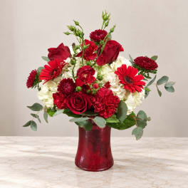 Red and white flower arrangement in a red vase