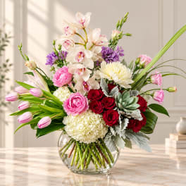 Mixed bouquet of orchids, roses, tulips, and chrysanthemums in a glass vase