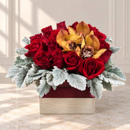 Red roses and yellow orchids in a square box with silver foliage