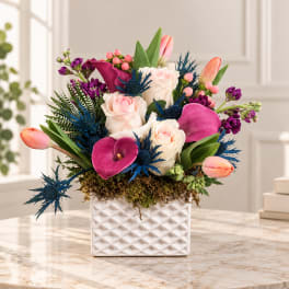 Mixed bouquet of roses, tulips, and calla lilies in a white vase