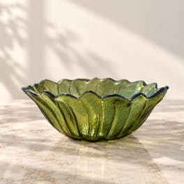 Green glass bowl with a scalloped rim on a marble surface