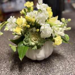 Yellow and white flowers arranged in a white pumpkin-shaped vase
