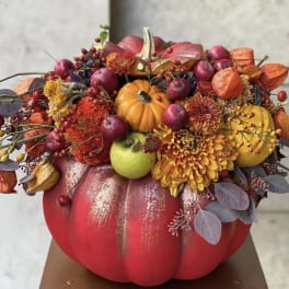 Fall floral arrangement in a painted pumpkin with small pumpkins and berries