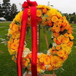 Large floral wreath of yellow and orange roses with a red ribbon