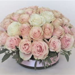 Round bouquet of pale pink and white roses in a low container