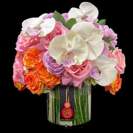Compact arrangement of orchids and roses in a leaf-lined glass cylinder vase