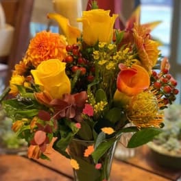 Yellow and orange floral arrangement in a clear glass vase