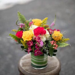 Colorful bouquet of roses and mixed flowers in a striped glass vase