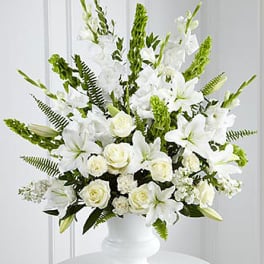 White floral arrangement in a white vase with tall green accents