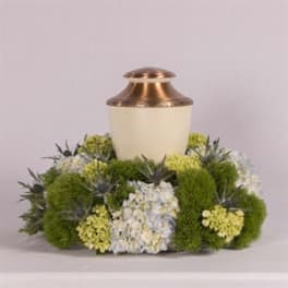 Funeral urn surrounded by green and white flowers