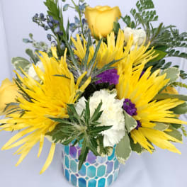 Yellow roses and white flowers in a blue mosaic vase