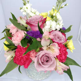 Mixed bouquet of pink and white flowers in a textured vase