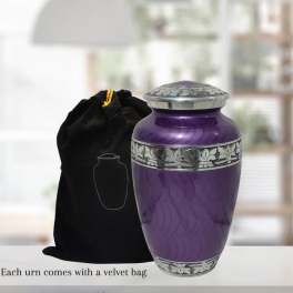 Purple memorial urn with silver detailing beside a black velvet bag
