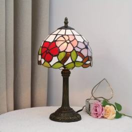 Stained-glass table lamp beside two artificial roses