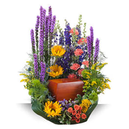 Tall floral arrangement with purple spikes, yellow blooms, and a wooden urn